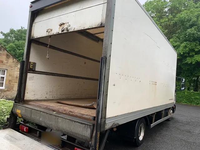 Large white box lorry with its rear shutter open and the tail lift lowered, ready to load for a house move