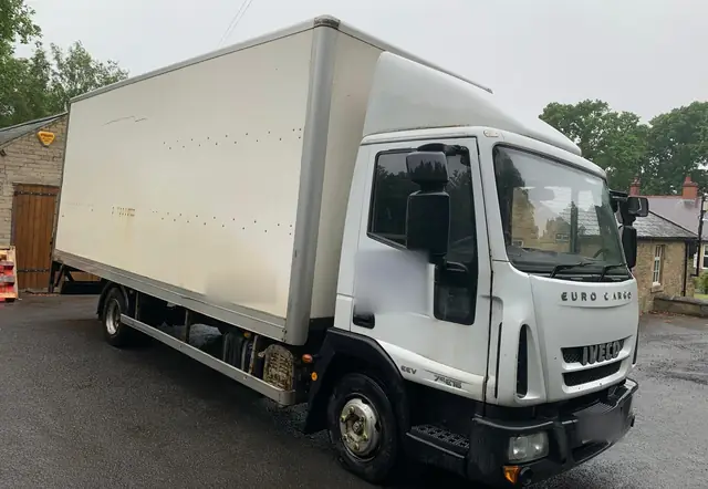 Large white box lorry parked on a yard, seen from the front corner, used for bigger house moves