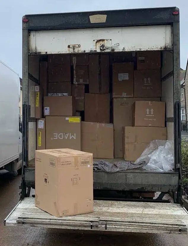 Luton van stacked with flat-pack furniture boxes, with one large box waiting on the lowered tail lift